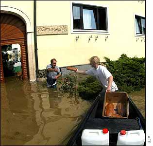 A firefighter (R) delivers bread and water to people who remain in their flooded houses in Lower Austria
