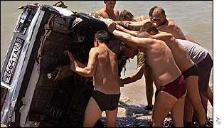 Rescue workers examine a car that was swept away