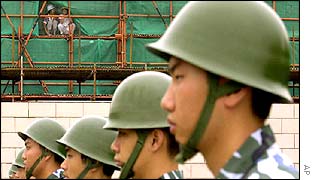 Construction workers watch soldiers drill in Shanghai