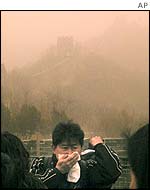 A visitor covers his mouth as a dust storm hits the Great Wall outside Beijing
