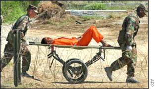 A detainee is carried on a stretcher at Camp X-Ray, Feb. 2002