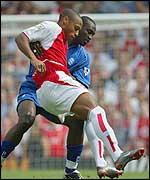 Thierry Henry golds off the challenge of Oliver Tebily