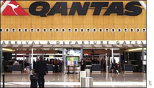 A lonely traveller passes under a Qantas sign at an airport