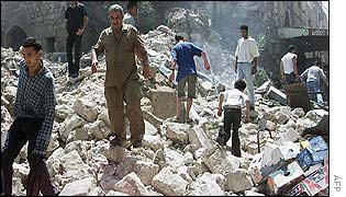 Palestinian men make their way through a pile of rubble after Israeli troops blew up a row of shops in Nablus