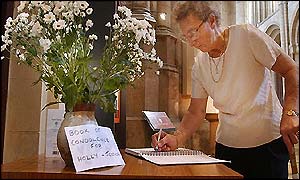 A woman signs a book of condolence