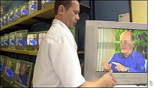 A salesperson sets a television while Brazilian presidential candidate Jose Serra speaks
