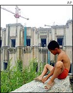 A boy sits in front of a wall of the Three Gorges dam