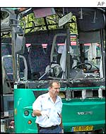 An Israeli policeman walks past a bus that was bombed on 4 August in Meron Junction