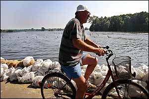 A local resident rides near a sandbagged riverbank as a result of rising floods in Weisen, Lower Saxony