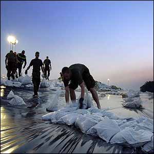Soldiers prepare sandbag layers over plastic on the Elbe River