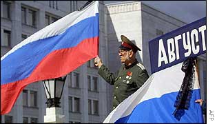 An officer holds the national flag of Russia in front of the Government House 