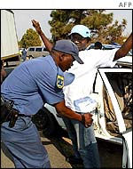 South African policeman searches a driver at a roadblock in Johannesburg