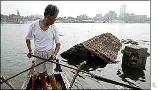 Man in boat passes submerged house 