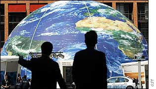 Delegates walk in front of a giant globe in Sandton Square