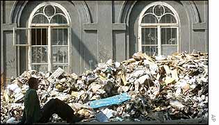 A man sits next to piles of garbage in Prague's Karlin district