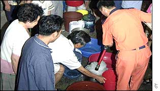 People gather to be given water by a rescue worker