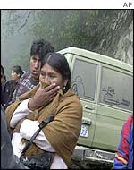 A woman watches rescuers at the crash site near La Paz