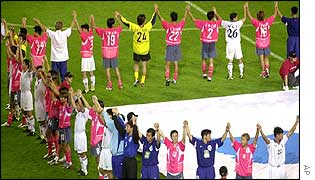 South and North Korean players hold hands on the pitch