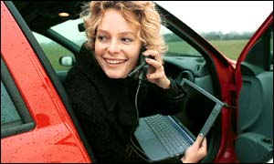 Presenter Kate Humble of BBC WebWise (1999) sits in a car using the internet with a laptop and mobile phone