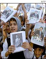 Iraqi children show pictures of Saddam Hussein in their textbooks