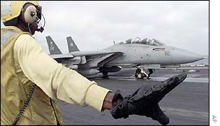 An aircraft director gives directions to the pilot of an F-14 on the flight deck of the USS George Washington aircraft carrier in the Arabian Sea 