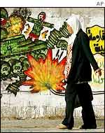 A woman walks past graffiti commemorating an attack on an Israeli tank