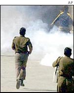 Indian security personnel chase Kashmiri protesters through tear gas