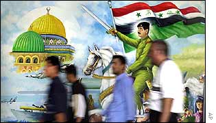 People walk past a mural in Baghdad