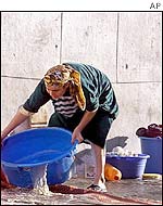 A Moroccan woman washes her linen in front of empty electoral posters in Casablanca