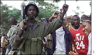 A rebel stands with a crowd chanting anti-government slogans