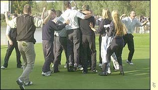 The European team swamp Paul McGinley on the green after the match winning putt