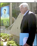Representative Jim McDermott walks past a picture of Saddam Hussein