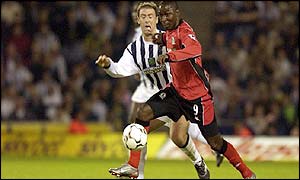 Andy Cole holds off the challenge of Sean Gregan