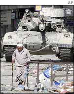 A man walks past a tank in Nablus
