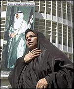 Iraqi woman by poster of Saddam in Baghdad