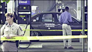 Police officer inspects a taxi where a man was shot dead at a petrol station 