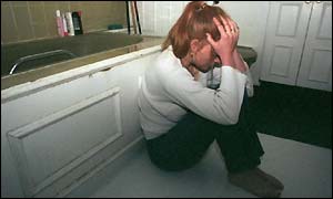 Woman cowering on the floor of the bathroom 