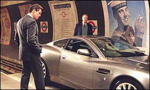 Bond (Pierce Brosnan) admires his new Aston Martin whilst Q (John Cleese) runs through it's technical abilities