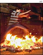 A boy jumps over a fire started during a protest in Ramallah
