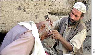 An Afghan barber shaves a man's head