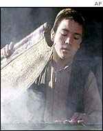 A youth cooks at a street barbeque in Kabul