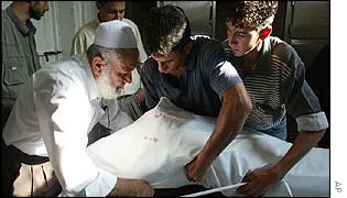 Family members wrap a victim in a shroud ahead of burial