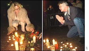Two people light candles and pray in front of the royal palace
