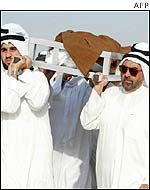 Men carrying one of Kuwaiti gunmen's bodies.