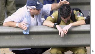 An Israeli police officer comforts a soldier at the site where a suicide bomber detonated his explosives belt at a bus stop 