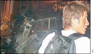 A foreign tourist looks on as a nearby disco burns