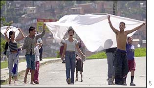 Residents carry a sheet to show they are peaceful in Medellin