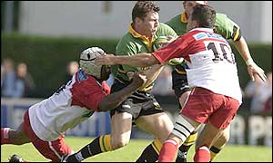 Saints' Jon Sleightholme is held back by Biarritz's Serge Betsen and Julien Peyrelongue