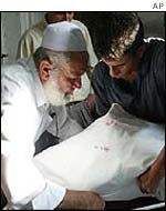 Family members wrap a dead relative ahead of burial