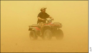 An Australian farmer rides through a duststorm 